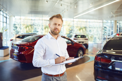 concessionnaire debout dans un parc auto